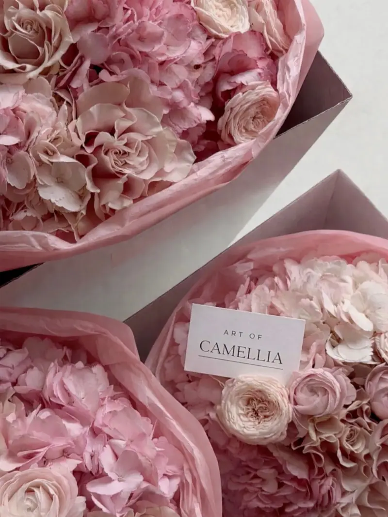 Zbliżenie różowych kwiatów i opakowań oznaczonych Art of Camellia